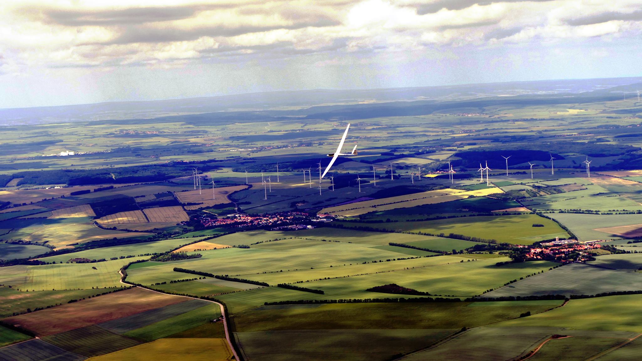 Segelflugzeug über der Thüringer Landschaft mit Feldern und Windrädern